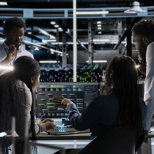 Data center programmers doing brainstorming, setting up machine learning systems handling information. Teamworking colleagues training neural networks to improve server farm operations
